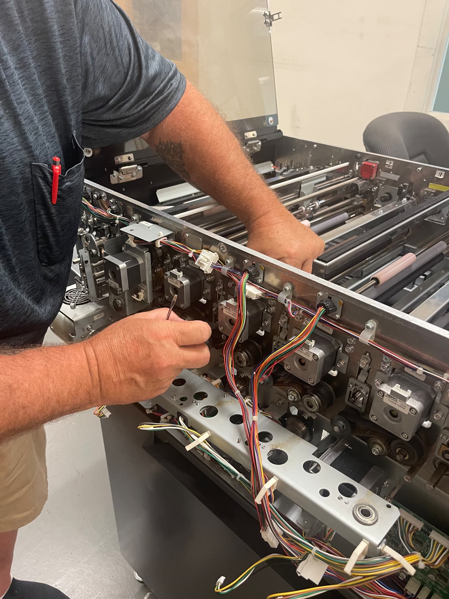 SBR-NE technician performing equipment service on Duplo print-finishing machinery